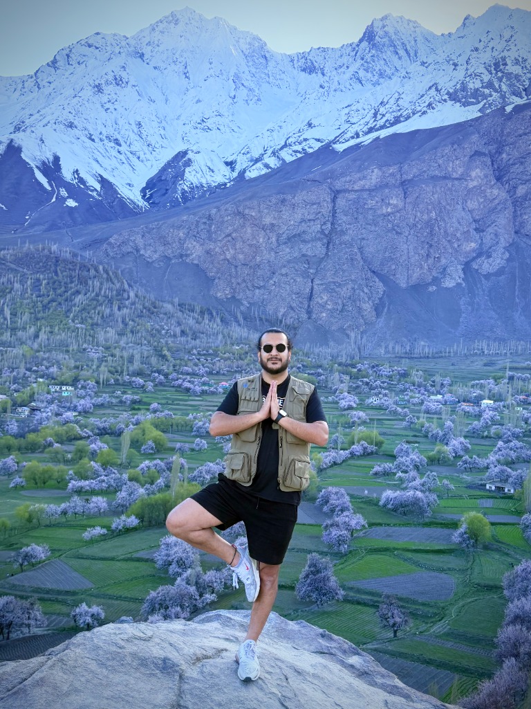 Hannan Balti — Client standing in tree pose in front of blossom trees and snowy peaks, Hunza Valley